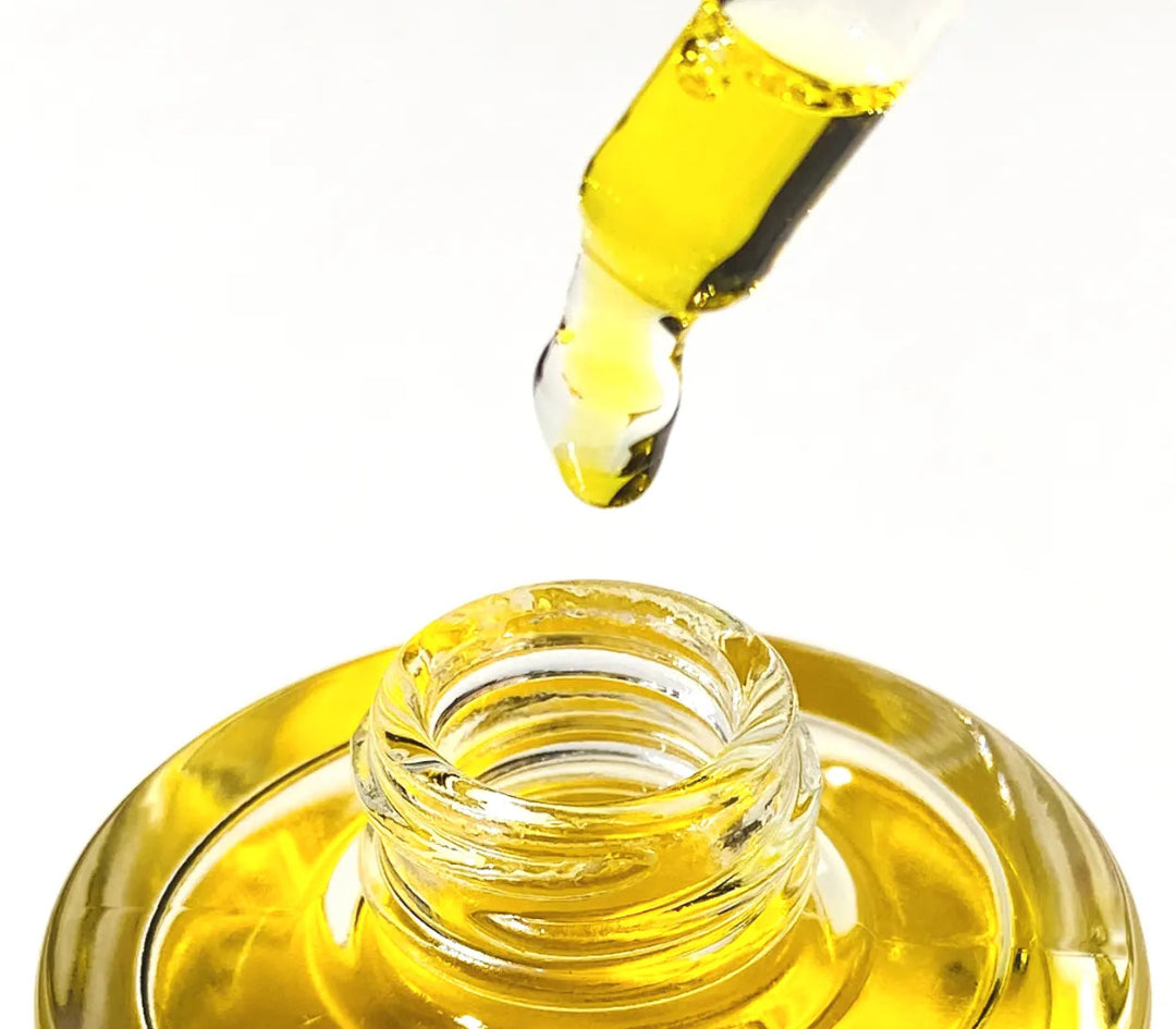 Bakuchiol Serum from By Valenti close up of a dropper dripping yellow serum back into the bottle on a white background