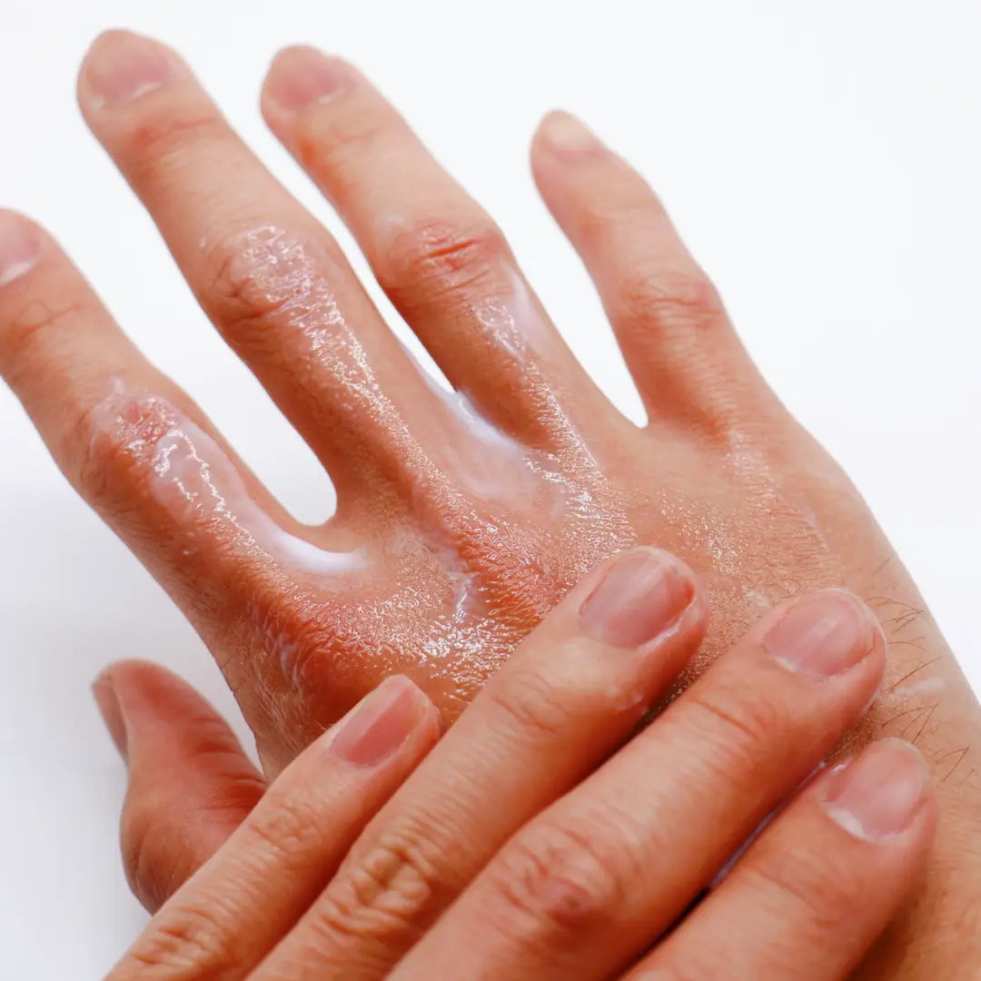 Close-up of hands with BY VALENTI hand lotion on a white background