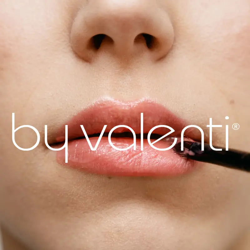 Close-up of a woman applying lipstick with 'by valenti' branding.