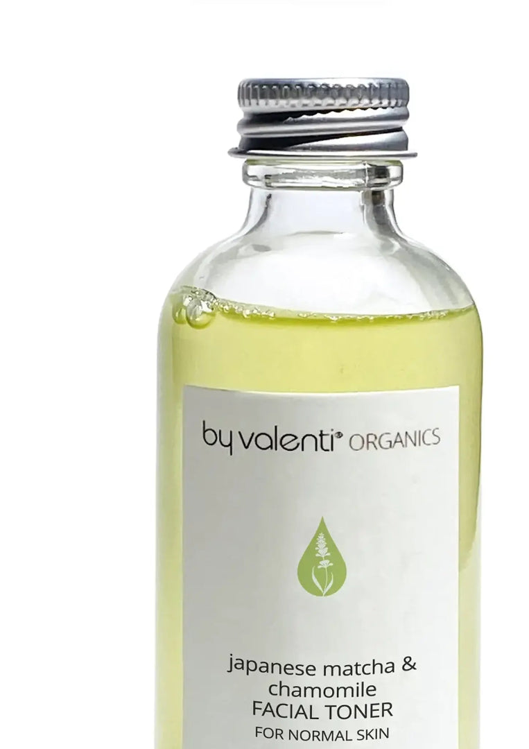 Clear glass bottle of BY VALENTI Japanese Matcha & Chamomile Facial Toner displaying its light green color, with an aluminium cap on a white background