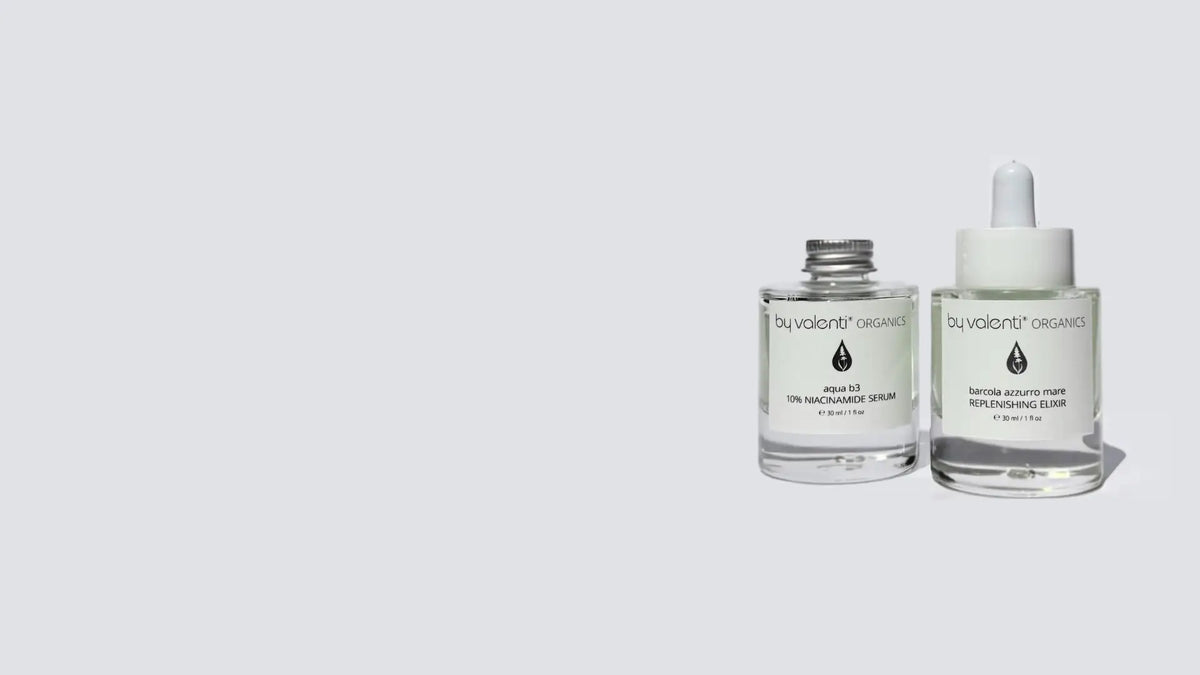 Two clear BY VALENTI Niacinamide Serum bottles with white labels on a light gray background. One bottle has a silver cap and the other has a white dropper top.