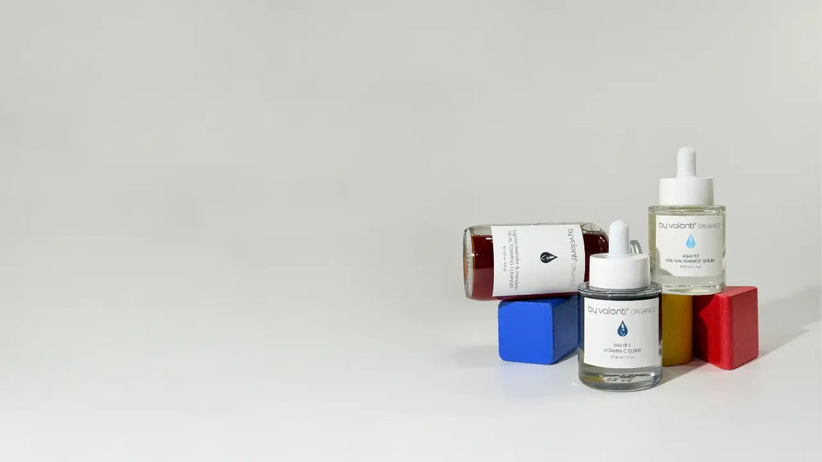 Three By Valenti skincare products with children wooden building blocks in blue, yellow and red over a white background