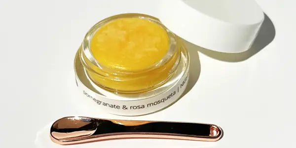 Jar of By Valenti Pomegranate & Rosa Mosqueta Eye Repair Balm with a spoon on a white background