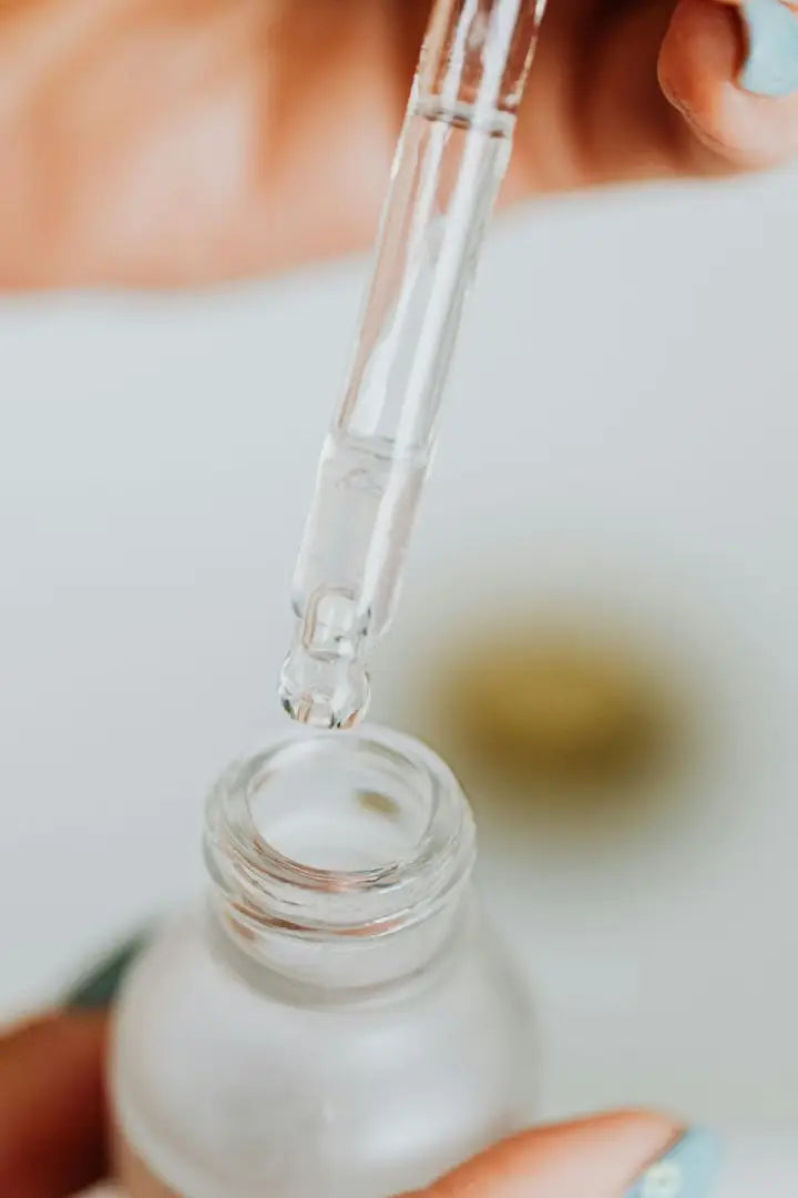 Close-up of a dropper being used to extract liquid from a bottle with a blurred background.