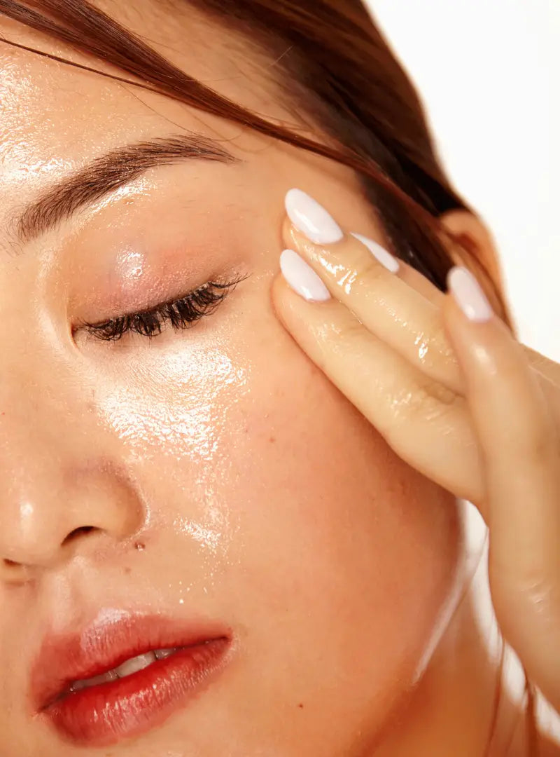 Close-up of a woman applying skincare product to their face.